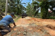 Alimuddin menyebar batu gunung untuk dijadikan fondasi jalan di Jalan Rusa, Kampung Harapan Jaya, Kecamatan Segah, Minggu (20/7/2025). (Sulaiman/BT)