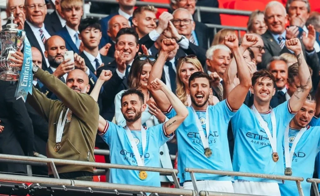 Pelatih Man City Pep Guardiola mengangkat trofi piala FA. (id.mancity.com)
