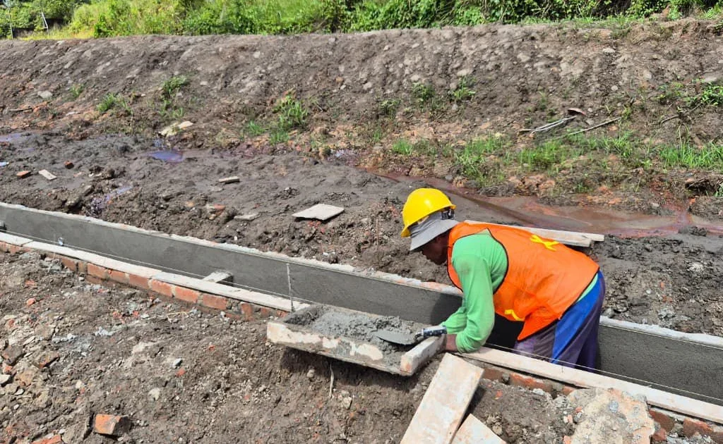 Pekerja sedang melaksanakan pekerjaan pembangunan cable duct dengan melakukan pekerjaan perapihan dan finishing permukaan saluran beton.