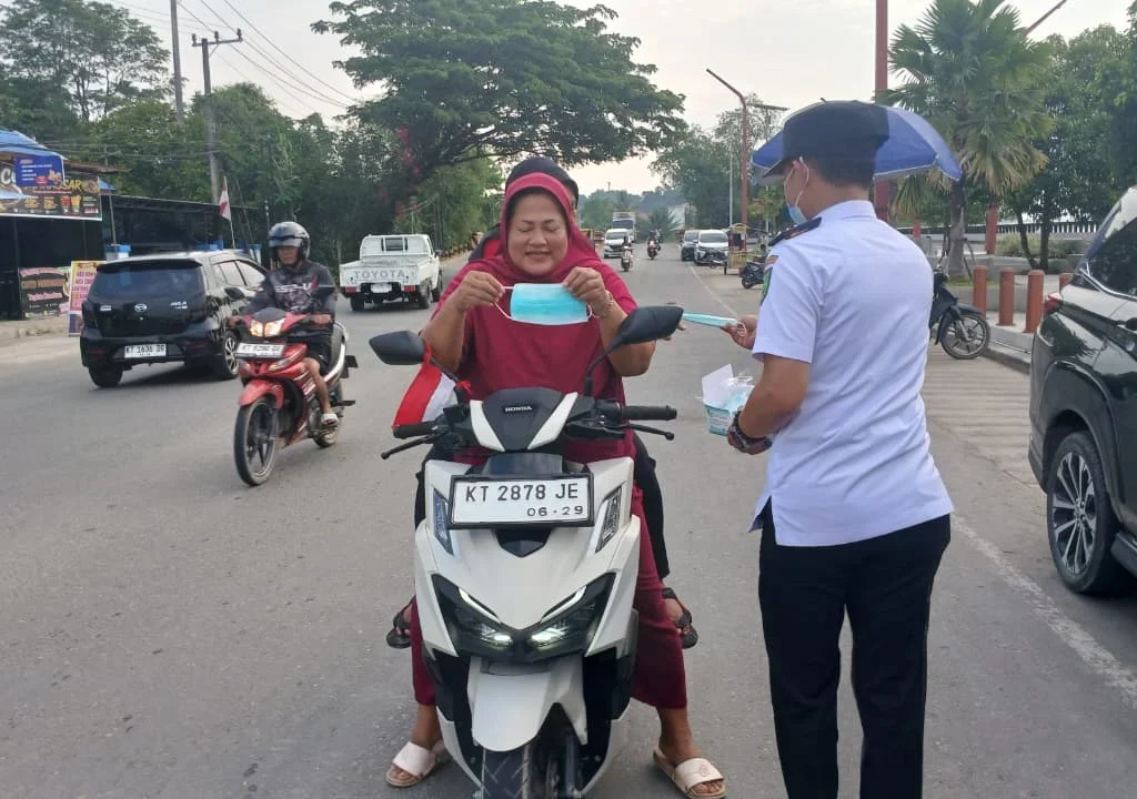Forkopimcam Teluk Bayur saat membagi masker gratis kepada warga di kawasan Teras Bandara Kalimarau, Rabu (26/8/2026). (Adrikni/BT)